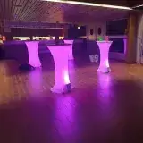 Mange-debout éclairés en rose dans un foyer, avant l’arrivée du public.