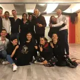 Un groupe d’amis dans une salle de danse, accroupis autour d’un t-shirt Bailando con Villa Vida.